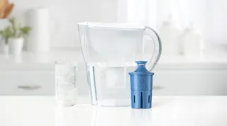 White Brita pitcher on kitchen counter, next to Brita Elite filter and water glass filled with ice and water.