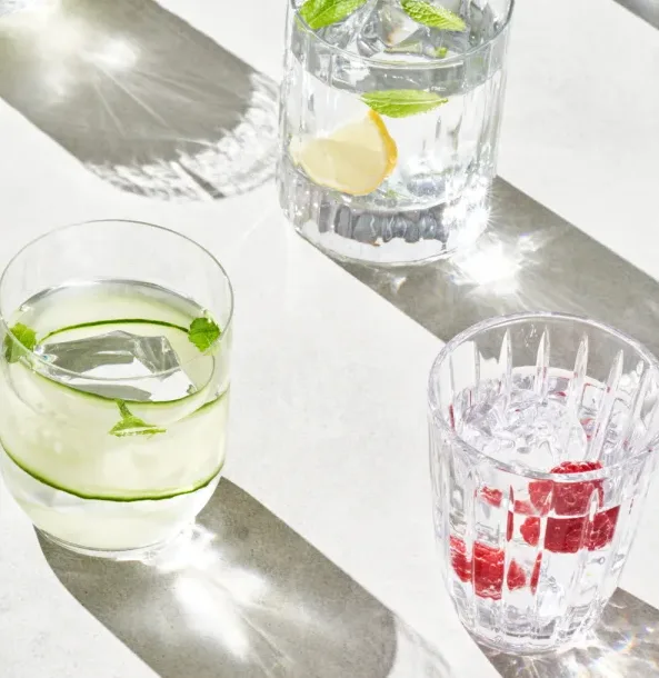 Several glasses of water with lemon, lime, and/or raspberries in them.