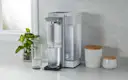 Brita Hub™ Countertop Water Filter System filling a glass of water, while placed on kitchen counter next to another glass.