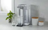 Brita Hub™ Countertop Water Filter System filling a glass of water, while placed on kitchen counter next to another glass.