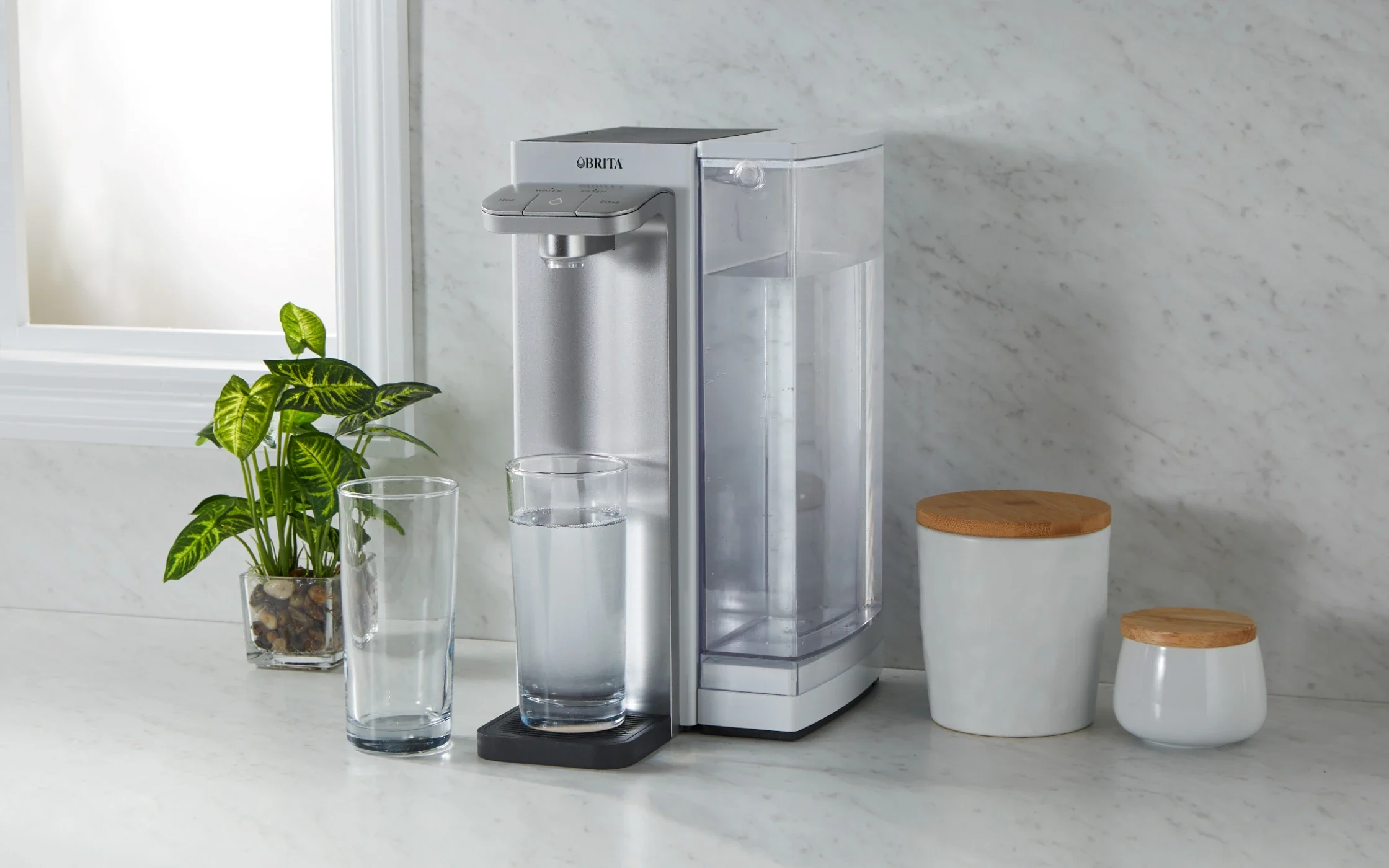 Brita Hub™ Countertop Water Filter System filling a glass of water, while placed on kitchen counter next to another glass.