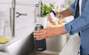 Person filling their Carbon, Stainless Steel, 32oz Brita water bottle with tap water from the sink.