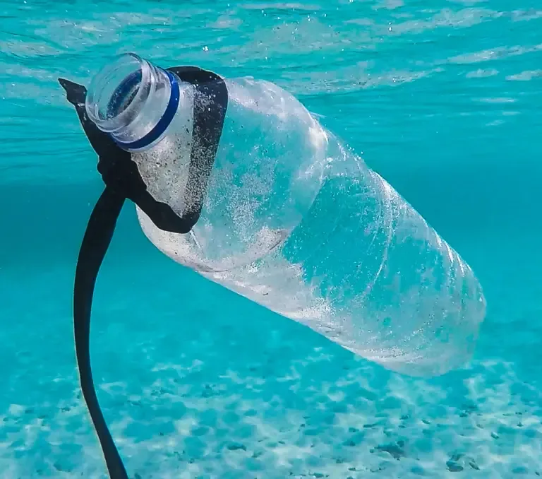 Plastic water bottle waste, floating in ocean.