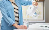 Person in kitchen pouring water into glass from Brita Denali Water Pitcher with Elite Filter.