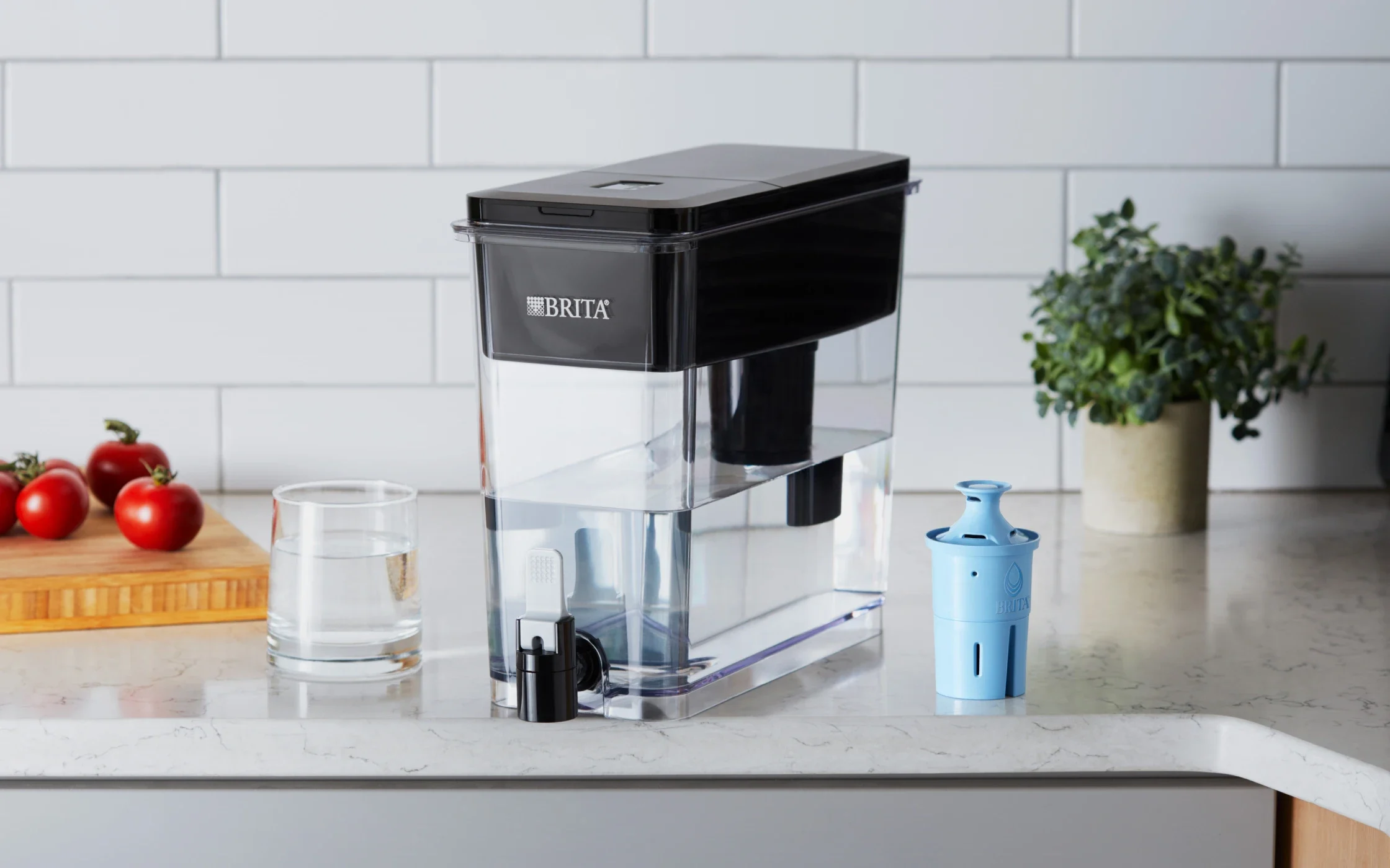 Black Ultramax Water Dispenser with Elite Filter on kitchen counter next to water glass.