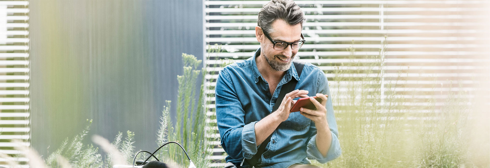 Ein Mann sitzt und bedient sein Smartphone