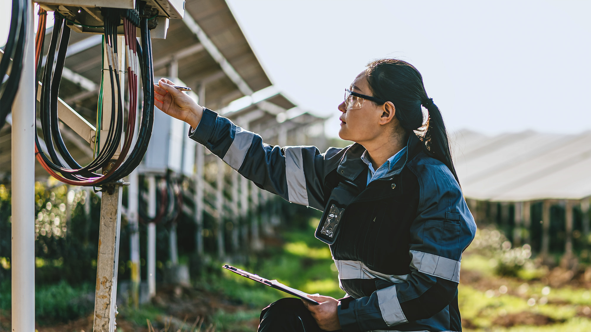 Eine Frau arbeitet am Stromkabel eines Solarpanels.