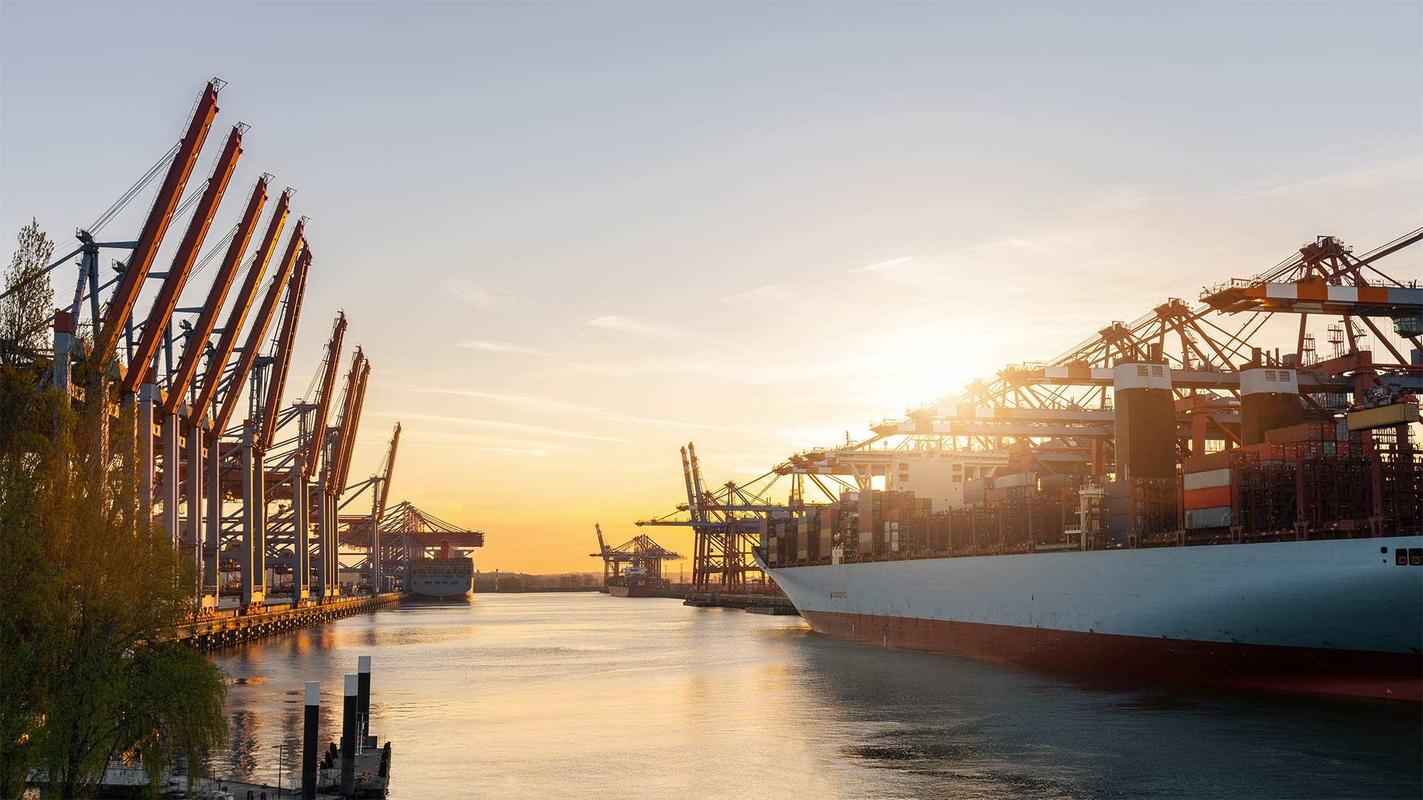 Container ship is lying in a port as the sun sets. The German government's innovation program supports the 5G research projects for an efficient and rapid rollout. 