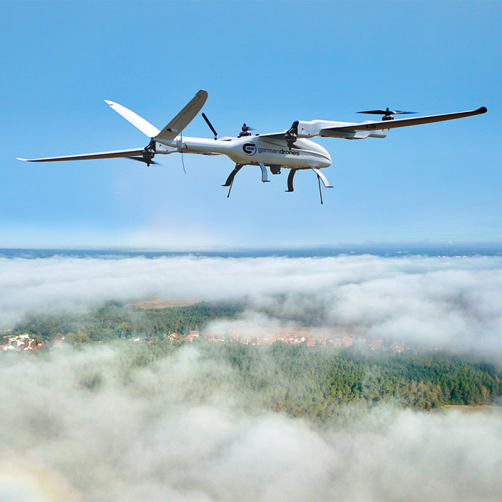 Eine Drohne fliegt über den Wolken bei blauem Himmel