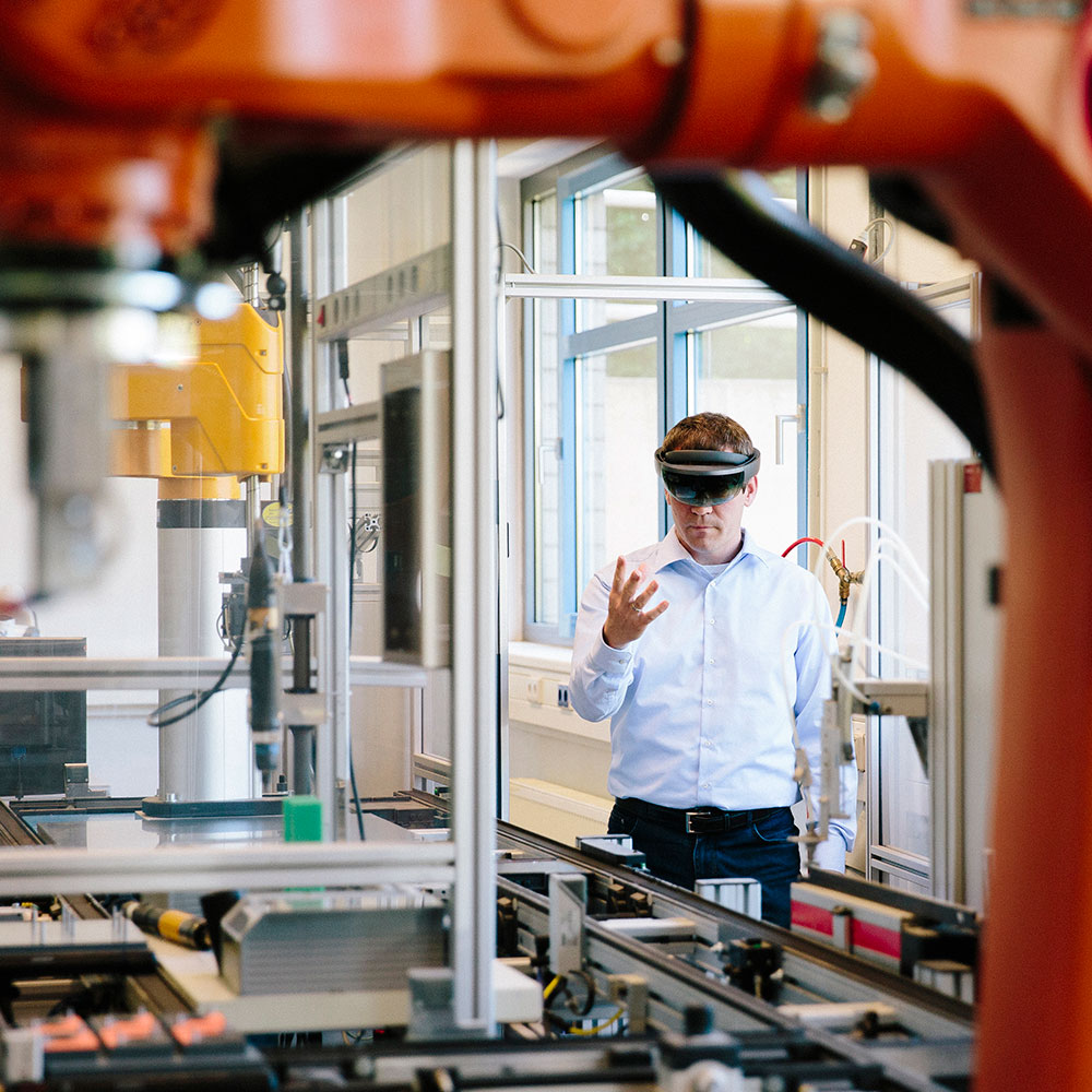 Ein Mann trägt Virtual Reality Brille in einem Produktionsraum. Durch den neuen Mobilfunkstandard 5G werden auch andere Technologien wie Virtual Reality die Industrie bereichern. 