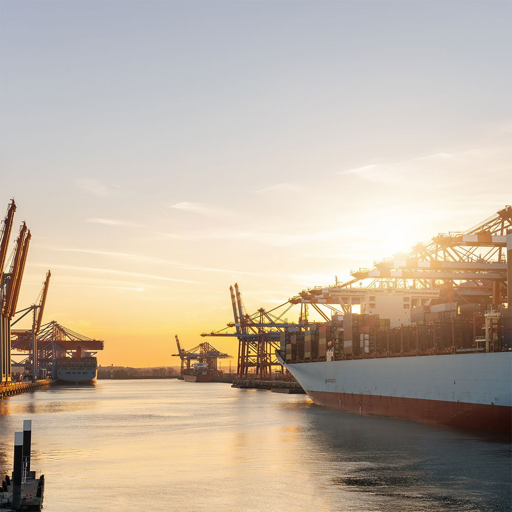 Container ship is lying in a port as the sun sets. The German government's innovation program supports the 5G research projects for an efficient and rapid rollout. 