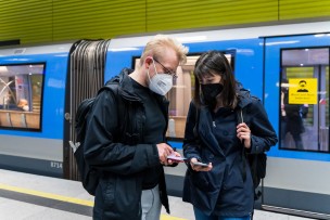 Zwei nebeneinander stehenden Menschen schauen im U-Bahnhof auf ihr Smartphone.