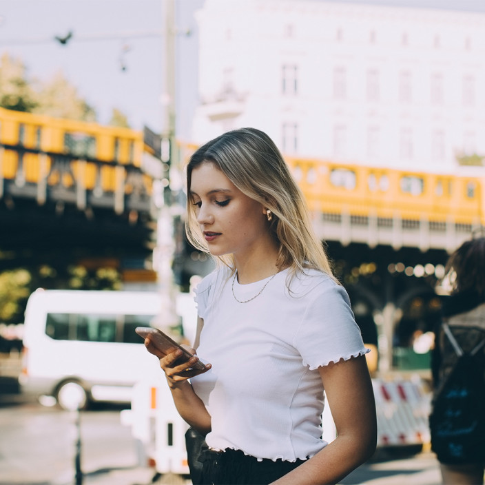 Eine Frau junge Frau nutzt ihr Mobiltelefon in der Stadt.