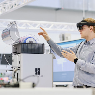 Ein Mann mit AR-Brille hebt eine Hand mit erhobenem Zeigefinger.