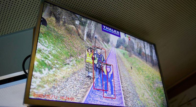 sodass eine Bilderkennung die Strecke (blau markiert) und Personen im Gleis (rot umrandet) identifizieren kann.