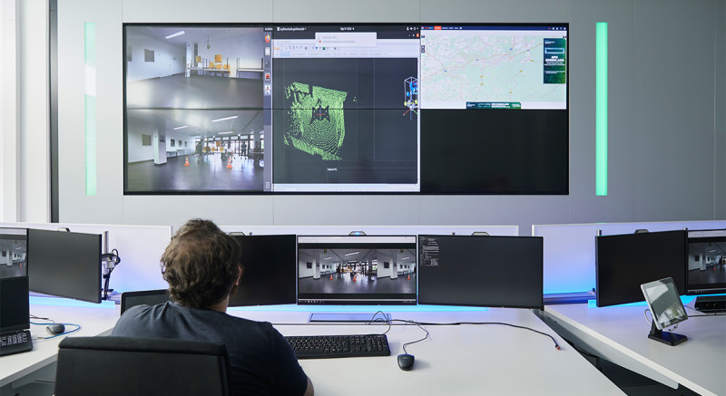 Der Leitstand mit den grünen Lichtern: Ein Mitarbeiter blickt auf Livebilder (links) und eine Simulation von der Umgebung des Transportroboters.