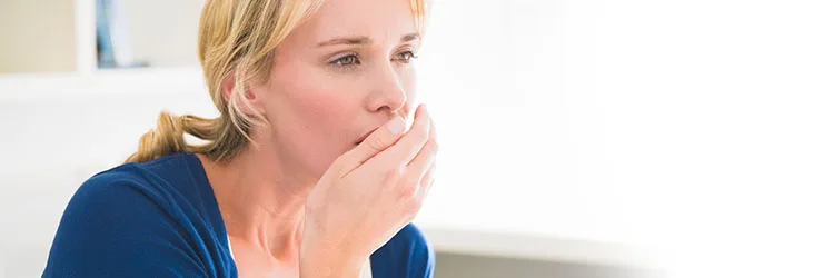 Woman testing to see if she has halitosis (bad breath)  