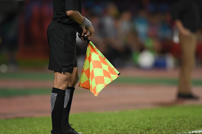 A referee holding an offside flag