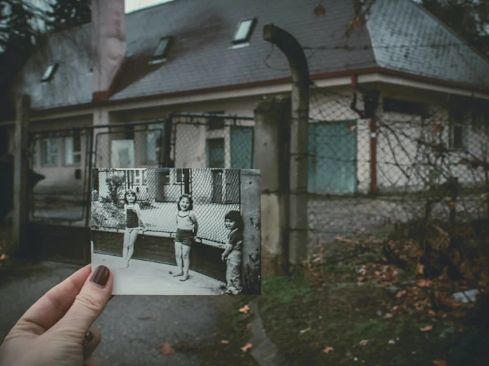A person looking at an old photo in the same spot where it was taken