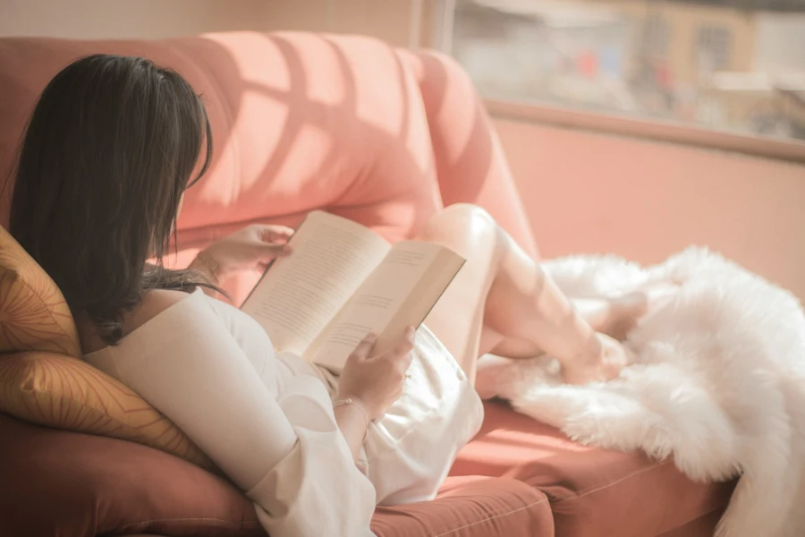 Woman reading on a pink sofa