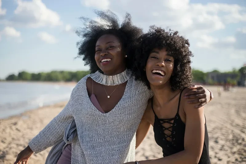 Two friends hugging and smiling at the beach