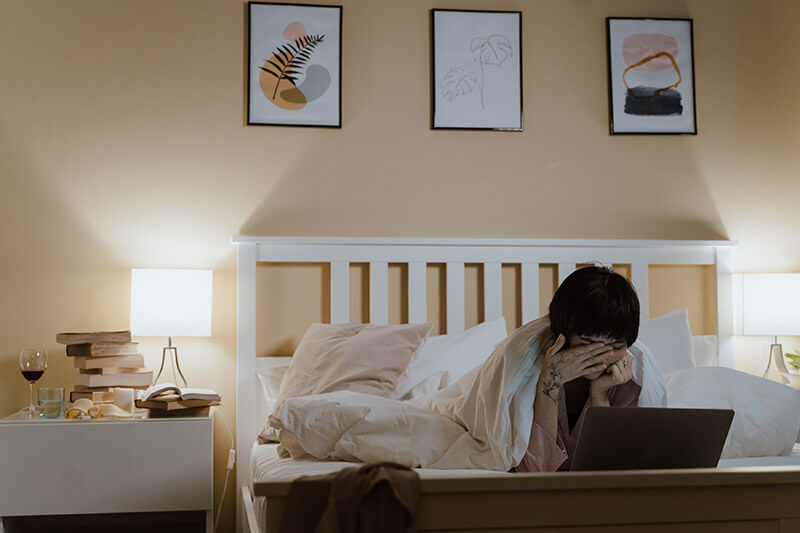 A person hunkers down in their bed feeling the affects of seasonal affective disorders.