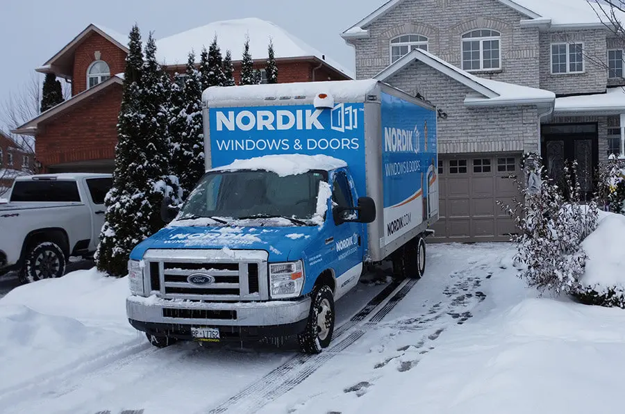 A Nordik installation truck drives through a suburban neighbourhood in the winter time.