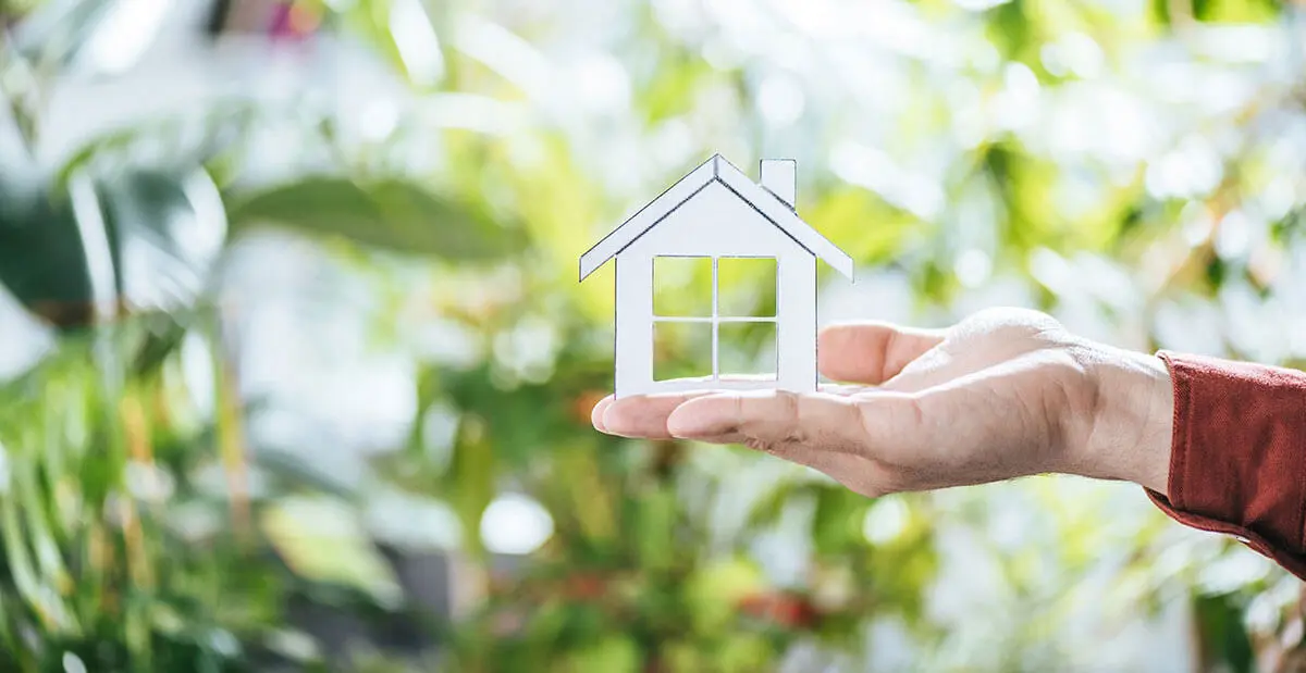 A man holds a same house in his hands reflecting the value of being energy conscious.