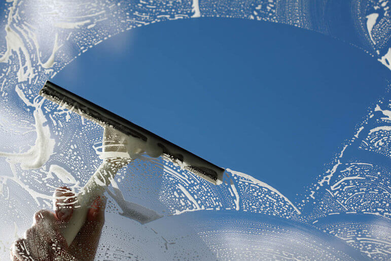 An underneath shot of a squeegee washing a soapy window.