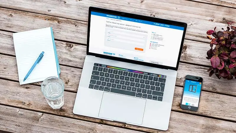 An overhead view of a laptop and mobile device looking at the Nordik Windows and Doors website.
