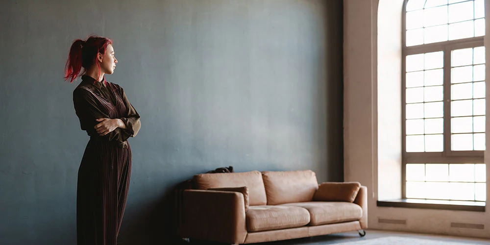 A woman looks out the window in a modern flannel jacket.