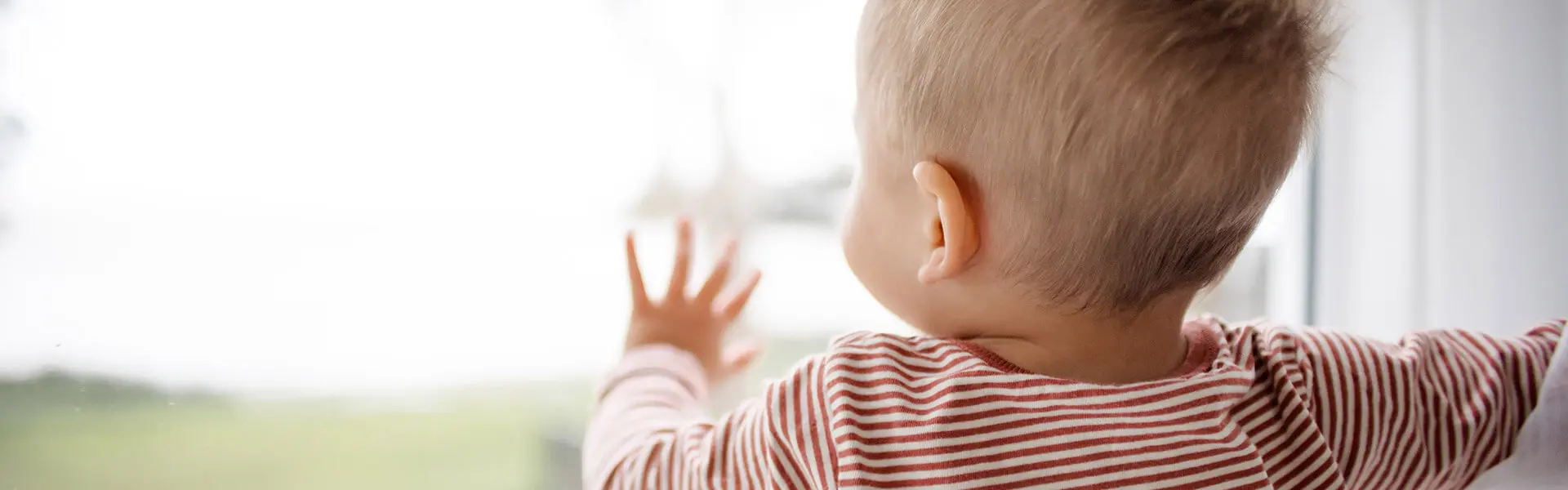 A little baby peers out of a window and its adorable.