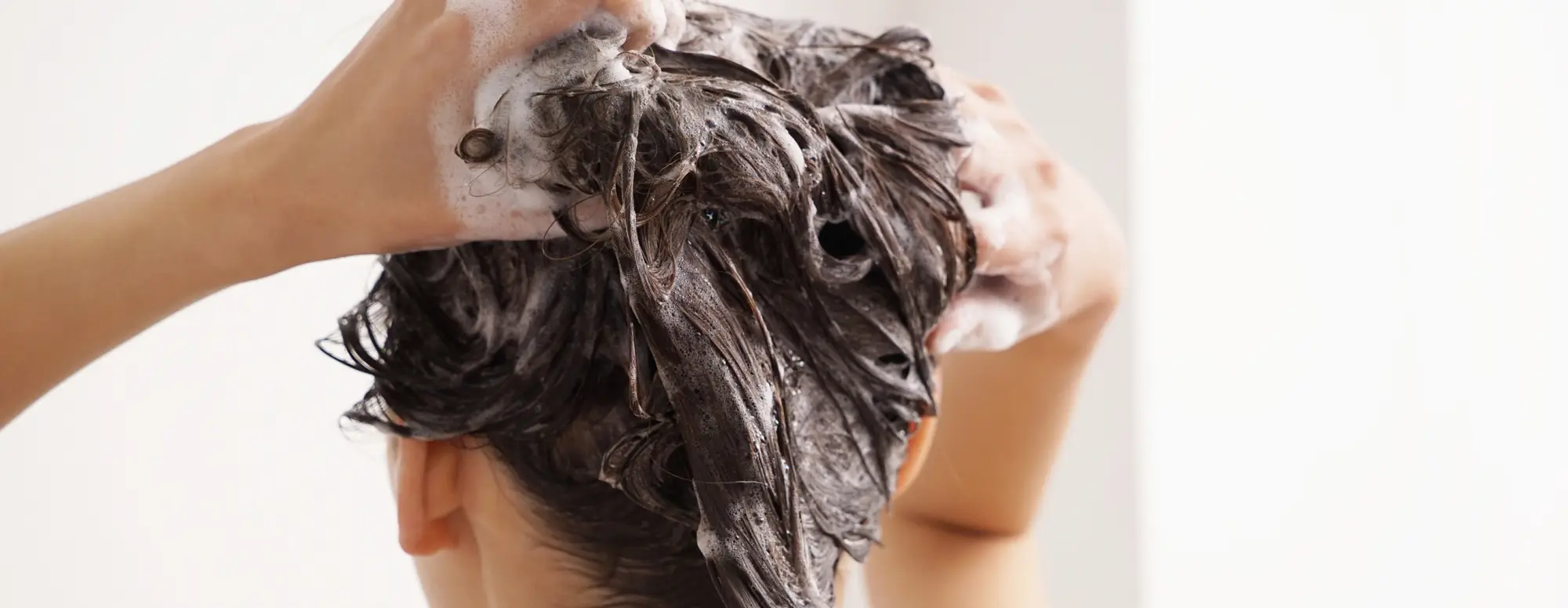 Mulher lavando o cabelo com produtos Pantene. É Importante mudar o shampoo 