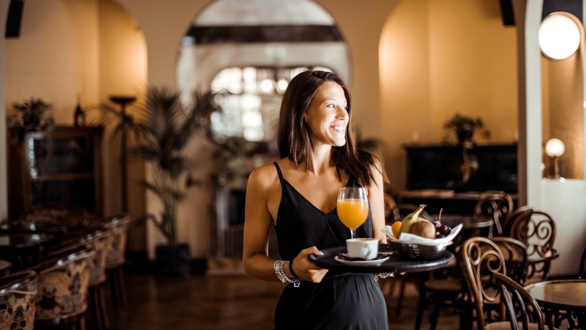 female pro in server assistant role bring food and drinks to a table.
