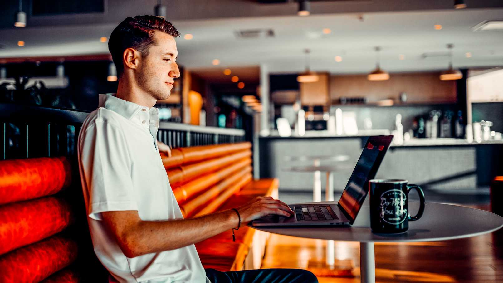 male manager typing on computer in dining room reviewing Pro applicants on Gigpro and selecting Pros to work the shift he posted