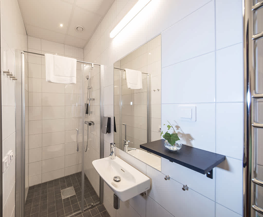 A nice and spacious bathroom with a shower and toilet in room Ida at Staykvick Boutique Hostel in Helsingborg.