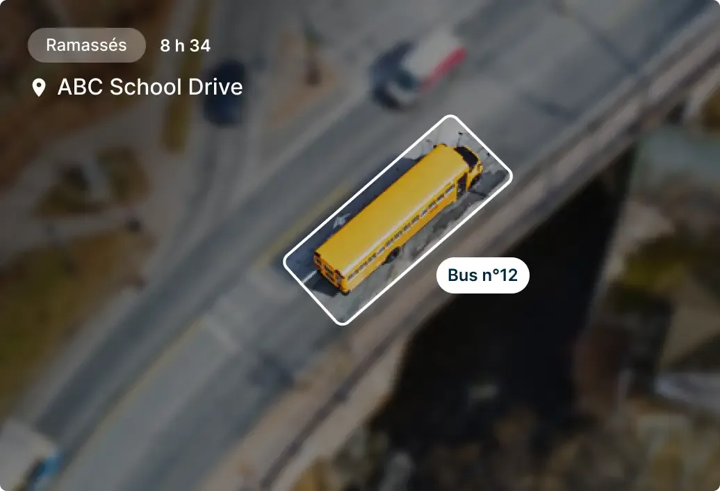 Vue aérienne d'un bus scolaire jaune n°12 sur ABC School Drive, avec indication "Ramassés" et horodatage 8h34.