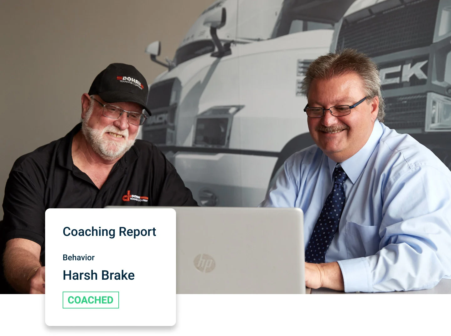 Two men smiling in front of a laptop. Overlay on the photo shows a coaching report card.