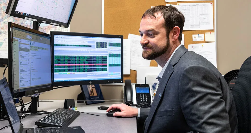 worker looking at a computer with two screens with stats in it