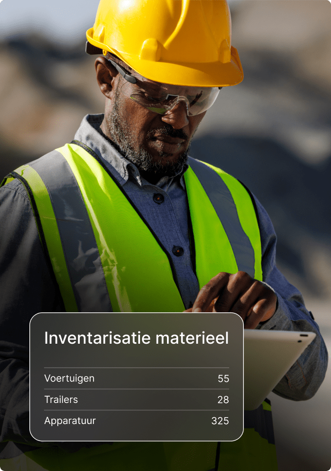 Bouwvakker met helm en veiligheidsvest gebruikt tablet om inventaris van voertuigen, trailers en apparatuur te controleren.