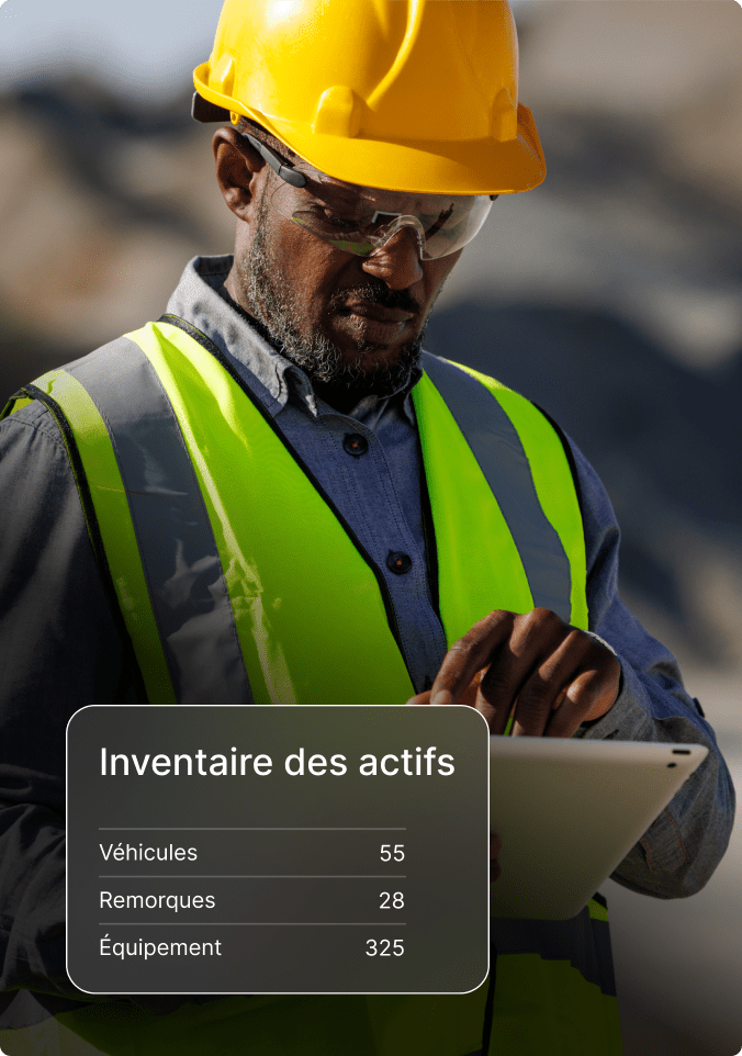 Ouvrier du bâtiment portant un casque et un gilet de sécurité utilise une tablette pour vérifier l'inventaire des actifs.