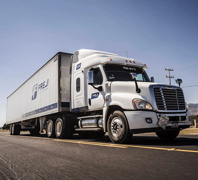 Camión de carga blanco de la empresa Freji circulando por una carretera bajo cielo azul despejado.