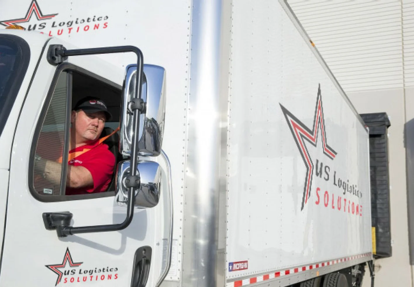 Foto van een chauffeur van US Logistics Solutions die uit het raam van een vrachtwagen kijkt
