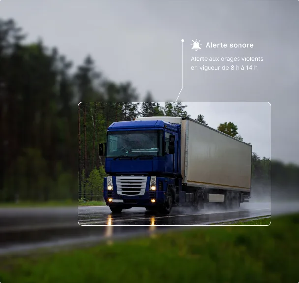 Semi-remorque bleu roulant sur une route mouillée par temps orageux, avec une alerte d’orage violent affichée au-dessus.