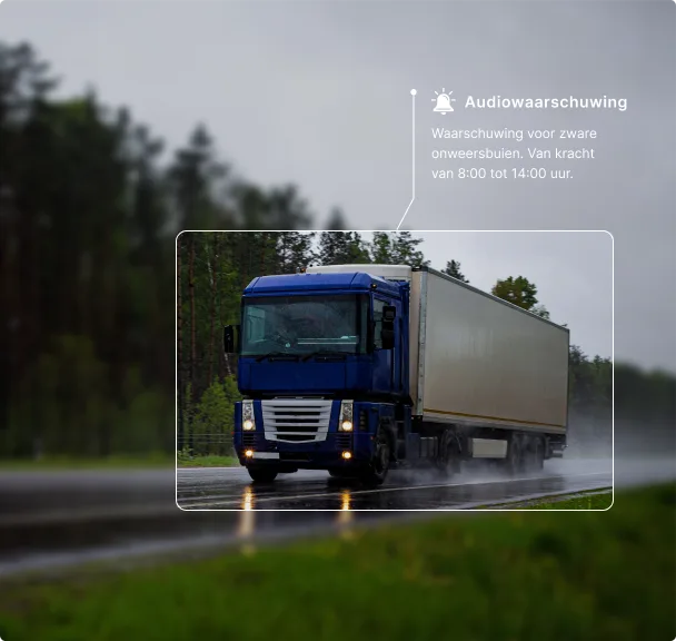 Blauwe vrachtwagen rijdt op natte weg tijdens stormachtig weer met daarboven een waarschuwing voor zwaar onweer.