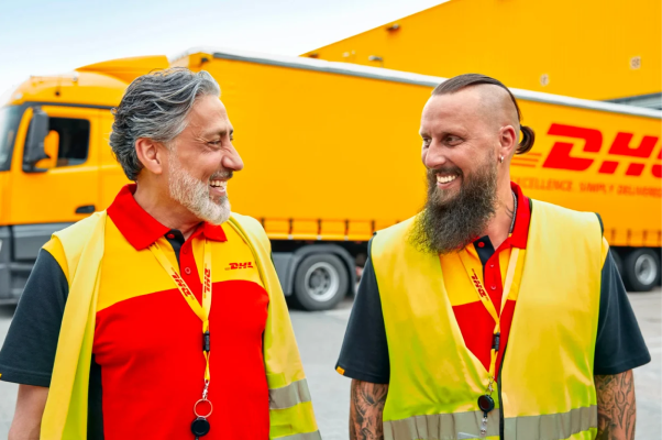 Two DHL employees standing in front of a DHL delivery truck.