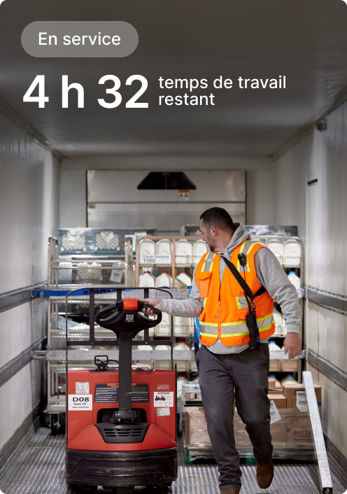 Un ouvrier en gilet de sécurité manutentionne un transpalette dans un camion, un écran indiquant qu’il reste 4 h 32 de poste.