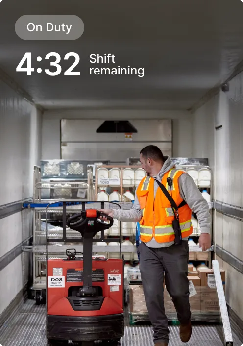 Worker in orange safety vest operating pallet jack in delivery truck with 4:32 shift remaining display.