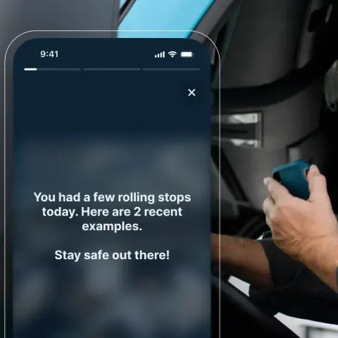 Phone screen showing driving safety alert about rolling stops, with a hand visible on steering wheel.
