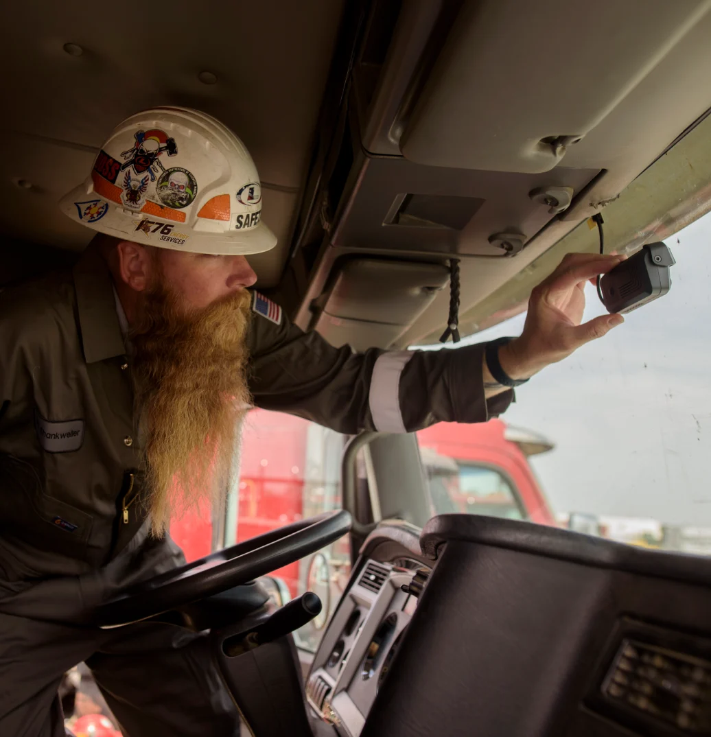 Chauffeur avec casque de chantier installant une caméra embarquée à l'intérieur de la cabine d'un camion